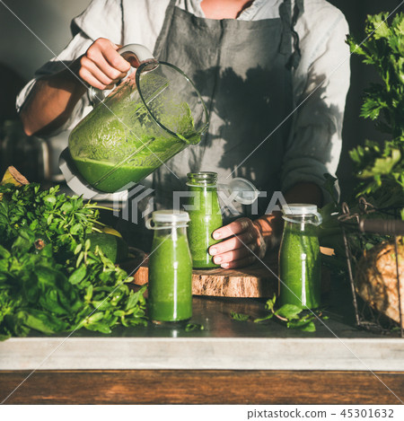 Woman pouring green smoothie from blender to bottle, square crop Woman pouring green smoothie from blender to bottle, square crop 45301632