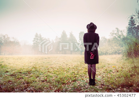 Girl in a coat and red gloves looks at the fog Girl in a coat and red gloves looks at the fog 45302477