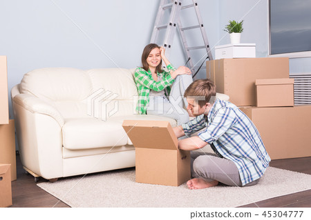 Moving, new apartment and relocation concept - young couple in the room surrounded by boxes having a 45304777