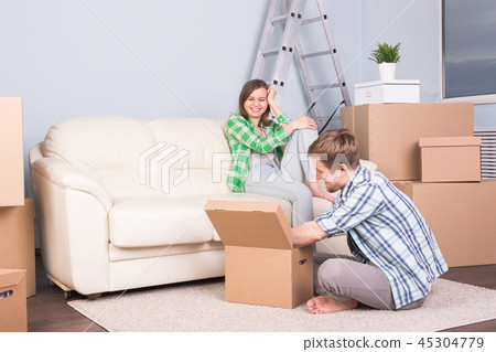 Moving, new apartment and relocation concept - Young man helping his wife with unpacking 45304779