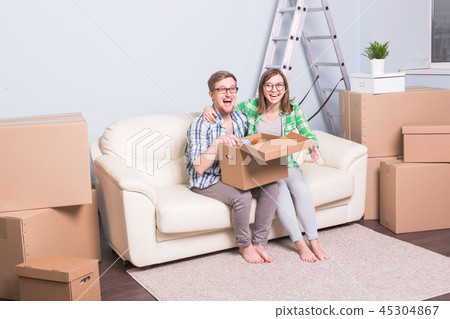 Family, new apartment, relocation and moving concept - a couple of young happy people opening their 45304867