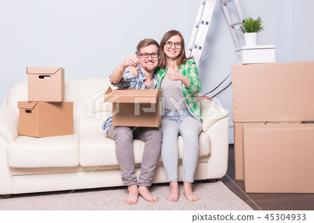Moving, relocation and new home concept - young couple having fun on the couch surrounded with boxes Moving, relocation and new home concept - young couple having fun on the couch surrounded with boxes 45304933