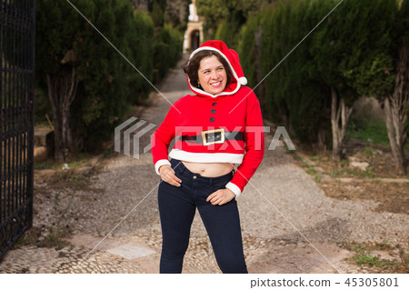Christmas, holidays, humor and people concept - young happy woman in santa suit dancing outdoors Christmas, holidays, humor and people concept - young happy woman in santa suit dancing outdoors 45305801