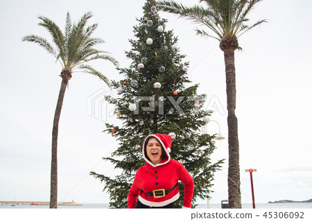 Christmas, holidays and humor concept - young happy woman have fun in christmas costume at summer Christmas, holidays and humor concept - young happy woman have fun in christmas costume at summer 45306092