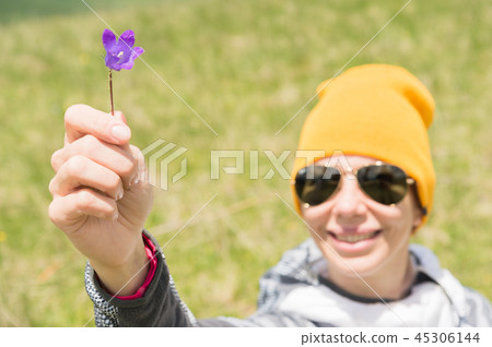 Portrait of a happy cheerful girl in a hat and sunglasses gives you a field flower against a 45306144