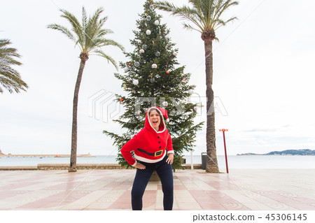 Christmas, holidays and humor concept - young happy woman have fun in christmas costume at summer Christmas, holidays and humor concept - young happy woman have fun in christmas costume at summer 45306145