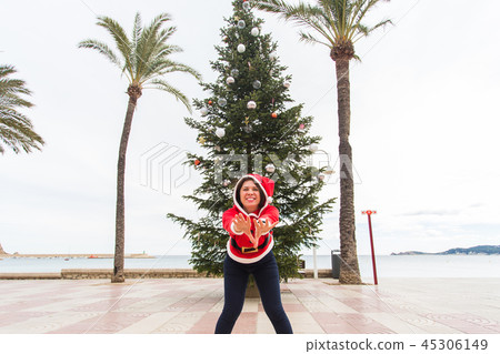 Christmas, holidays and humor concept - young happy woman have fun in christmas costume at summer Christmas, holidays and humor concept - young happy woman have fun in christmas costume at summer 45306149