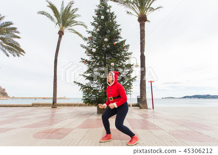Christmas, holidays and humor concept - young happy woman have fun in christmas costume at summer Christmas, holidays and humor concept - young happy woman have fun in christmas costume at summer 45306212
