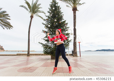 people, holidays and christmas concept - young funny and expressive woman dressed as santa claus 45306215