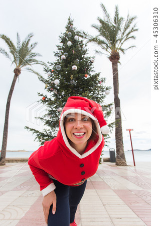 Christmas, holidays and humor concept - young happy woman have fun in christmas suit at summer near Christmas, holidays and humor concept - young happy woman have fun in christmas suit at summer near 45306310