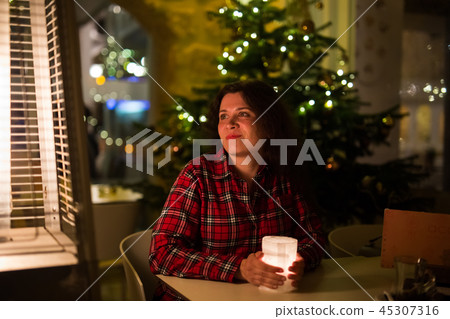 Holidays and people concept - Beautiful woman in cafe near Christmas tree background 45307316