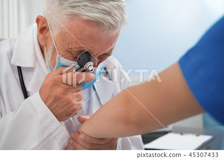 Doctor diagnosing disease of skin on patient's hand. 45307433