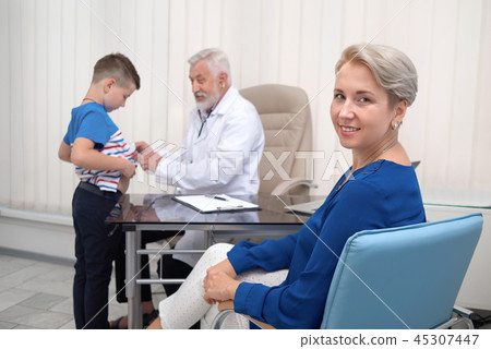 Mother smiling, waiting on doctor examining her son. Mother smiling, waiting on doctor examining her son. 45307447