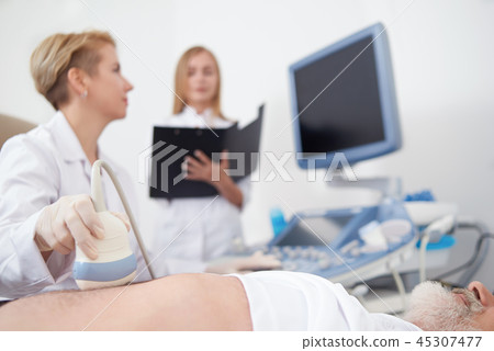 Doctor examining with ultrasound diagnostics man's belly. Doctor examining with ultrasound diagnostics man's belly. 45307477