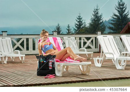 Hot girl lying on white lounger with towel in pink strip. Hot girl lying on white lounger with towel in pink strip. 45307664
