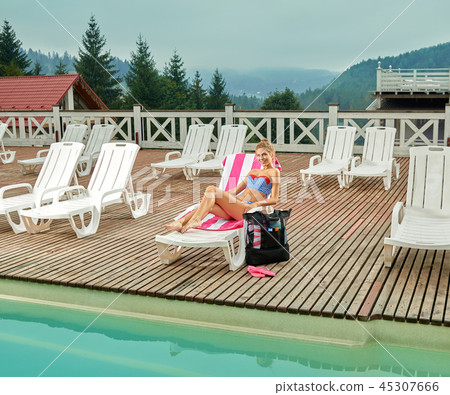 Girl lying on lounger near pool and tanning at daytime. Girl lying on lounger near pool and tanning at daytime. 45307666