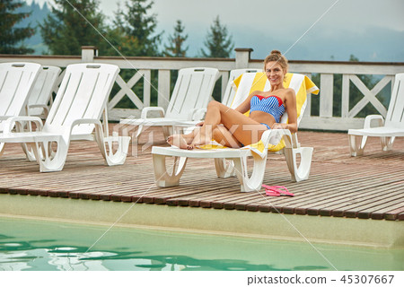 Woman enjoing her vacation, lying on beach chair near pool. 45307667