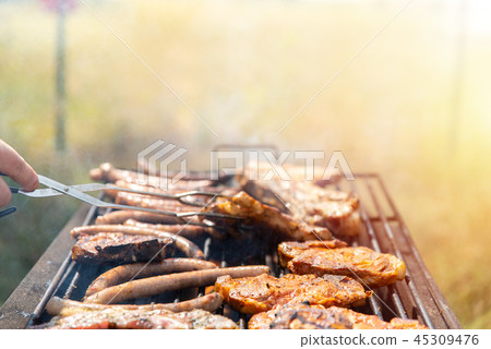 Meats being barbecued, fry steaks, meat ribs and sausages. Weekend with family and friends outdoor Meats being barbecued, fry steaks, meat ribs and sausages. Weekend with family and friends outdoor 45309476