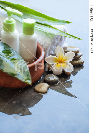 Spa bottle in bowl of water, towel and flower 45309905