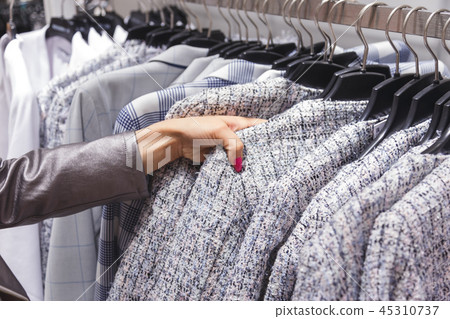 Woman choices a wool coat on hangers in the store. Woman choices a wool coat on hangers in the store. 45310737