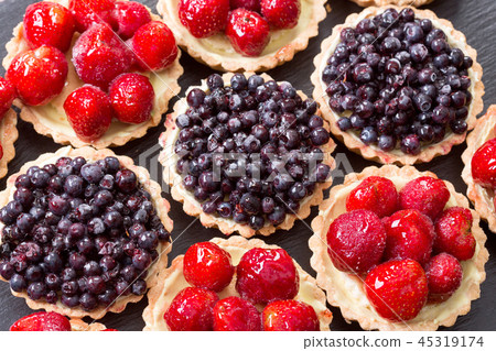 Fruit dessert tarts with strawberry and blueberry on wooden table. 45319174