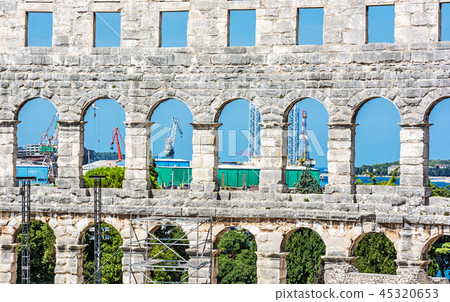 Pula Arena and cranes in cargo port, Croatia 45320653