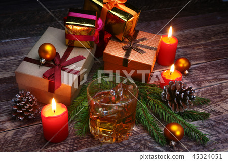 Glass with cognac or whiskey, Christmas balls and candles. New Year's tree, balls and glass with Glass with cognac or whiskey, Christmas balls and candles. New Year's tree, balls and glass with 45324051