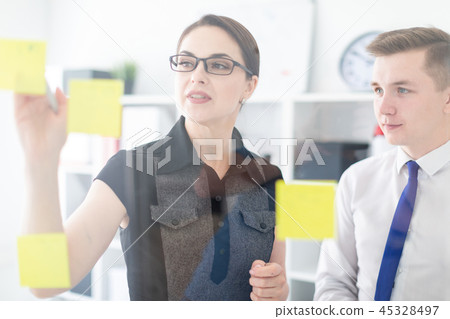 Young people are discussing in the office near the Board with stickers. 45328497