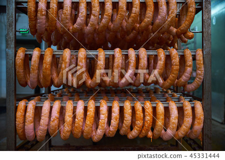 Raw sausages on racks in storage room at meat processing factory 45331444