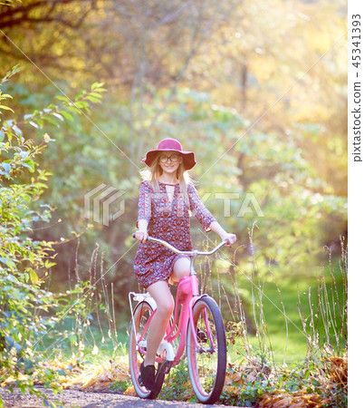 Blond fashionable long-haired attractive girl in short dress with lady bicycle in sunny park. Blond fashionable long-haired attractive girl in short dress with lady bicycle in sunny park. 45341393