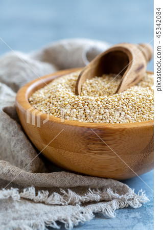 Raw quinoa and a scoop in a wooden bowl. Raw quinoa and a scoop in a wooden bowl. 45342084