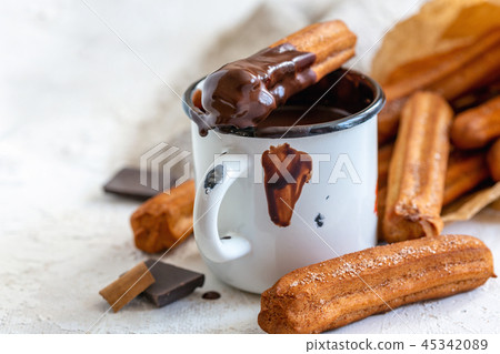 Churros with cinnamon in mug of hot chocolate. Churros with cinnamon in mug of hot chocolate. 45342089