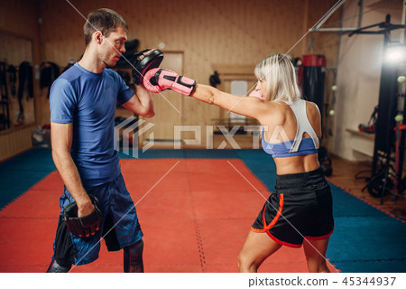 Female kickboxer on workout with personal trainer Female kickboxer on workout with personal trainer 45344937