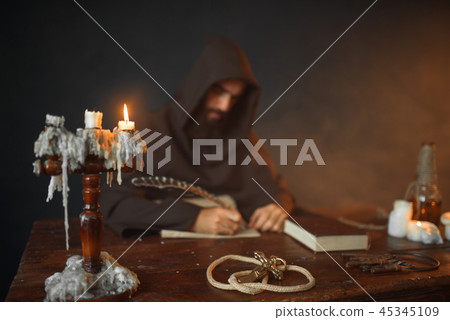 Medieval monk sitting at table and write, top view Medieval monk sitting at table and write, top view 45345109