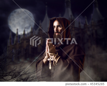 Medieval monk praying against castle and full moon Medieval monk praying against castle and full moon 45345285