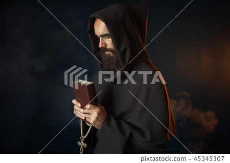 Medieval monk praying with book and cross in hands Medieval monk praying with book and cross in hands 45345307