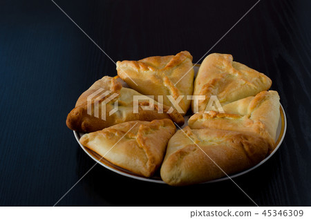A plate with fresh pies on a black wooden table A plate with fresh pies on a black wooden table 45346309