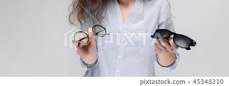 Young brunette girl with glasses. The girl is holding two pairs of glasses. Young brunette girl with glasses. The girl is holding two pairs of glasses. 45348210