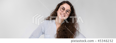 Portrait of a happy young girl in glasses. Beautiful young girl on a gray background. A young girl 45348232
