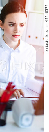Young girl in the office working with documents at the computer. Young girl in the office working with documents at the computer. 45348372