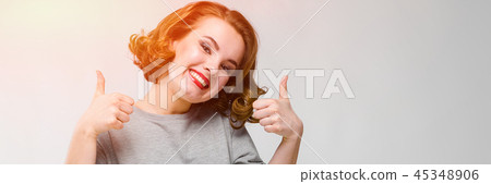 Charming young girl in a gray T-shirt on a gray background. Girl showing class sign Charming young girl in a gray T-shirt on a gray background. Girl showing class sign 45348906