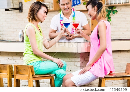 Two women holding red and blue cocktail 45349299