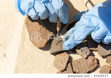 Hands archaeologist cleaned with a scraper of clay from a fragment of an ancient vessel 45349577