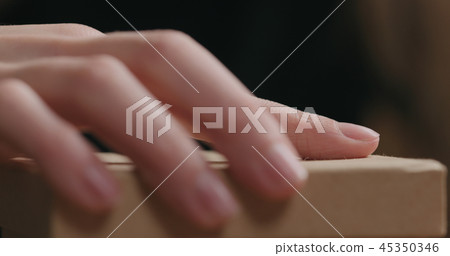 closeup shot of young female hands unties red ribbon bow on craft paper gift box closeup shot of young female hands unties red ribbon bow on craft paper gift box 45350346