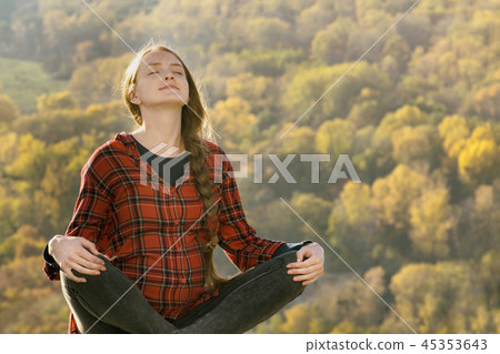 Pregnant woman sits on a hill with her eyes closed 45353643