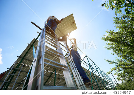 Professional mounters team keeping colar panel, installing on carcass. Professional mounters team keeping colar panel, installing on carcass. 45354947