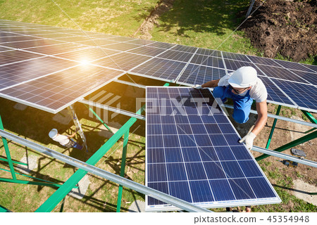 Mounting solar batteries on green metallic carcass by professional workers. Mounting solar batteries on green metallic carcass by professional workers. 45354948