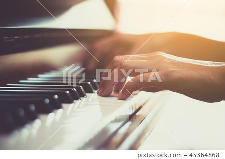 Close up of happy woman's hand playing the piano in the morning. Close up of happy woman's hand playing the piano in the morning. 45364868