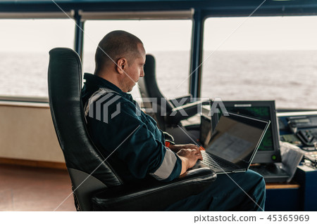 Marine navigational officer is using laptop or notebook at sea 45365969