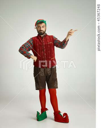 friendly man dressed like a funny gnome posing on an isolated gray background friendly man dressed like a funny gnome posing on an isolated gray background 45367248